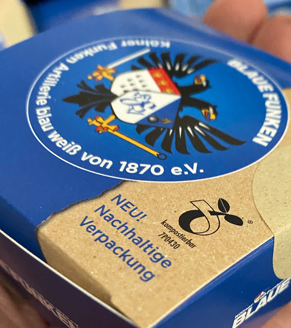 Verpackung der Artillerie Blau Weiß von 1870 e.V. mit dem Hinweis auf nachhaltige und kompostierbare Verpackung. Logo und Wappen gut sichtbar.