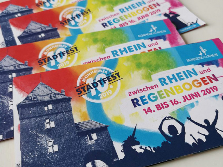 Bunte Werbebroschüren für das Monheimer Stadtfest 2019, das vom 14. bis 16. Juni unter dem Motto "zwischen Rhein und Regenbogen" stattfindet.