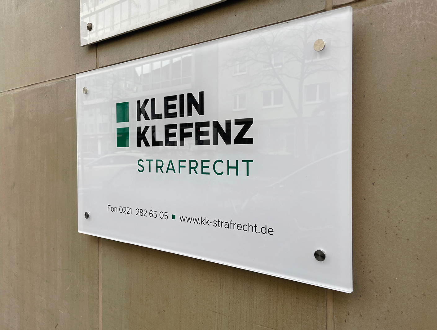 Schild der Kanzlei Klein Klefenz für Strafrecht mit Kontaktdaten und Website. Professionelles Design an der Fassade eines Bürogebäudes in urbaner Umgebung. Corporate Design Köln