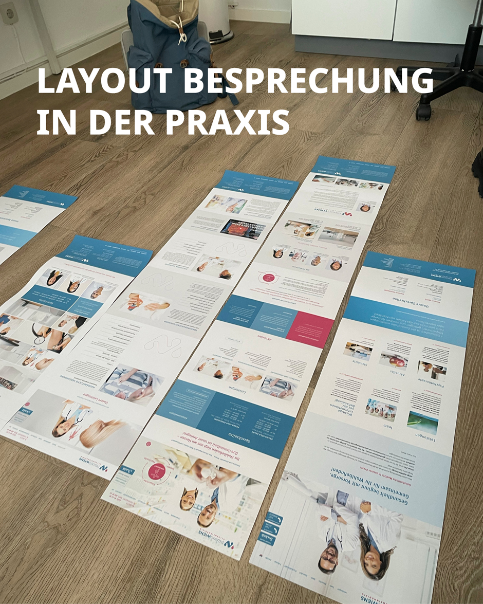 Layoutbesprechung in der Praxis mit verschiedenen Informationsblättern über medizinische Dienstleistungen auf einem Holzboden. Fokus auf Design und Präsentation.